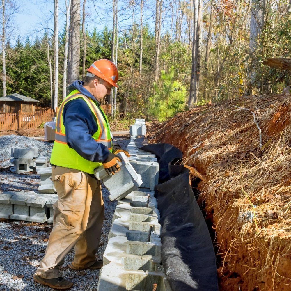 In process of developing new property construction worker is building a retaining wall using cement